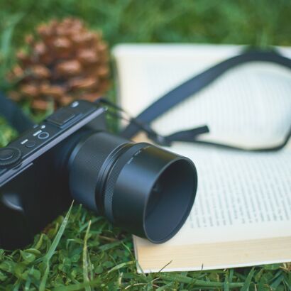 Auf einer Wiese liegen ein Buch und eine Kamera © pixabay